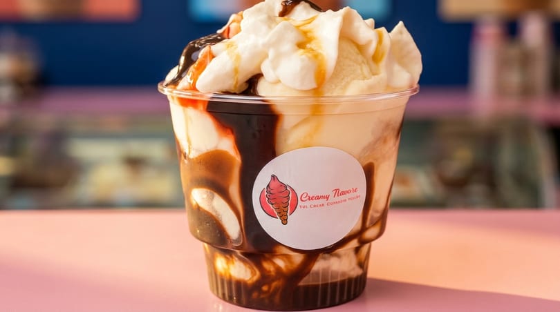 Creamy Flavore ice cream sundae with chocolate and caramel drizzle, topped with whipped cream.